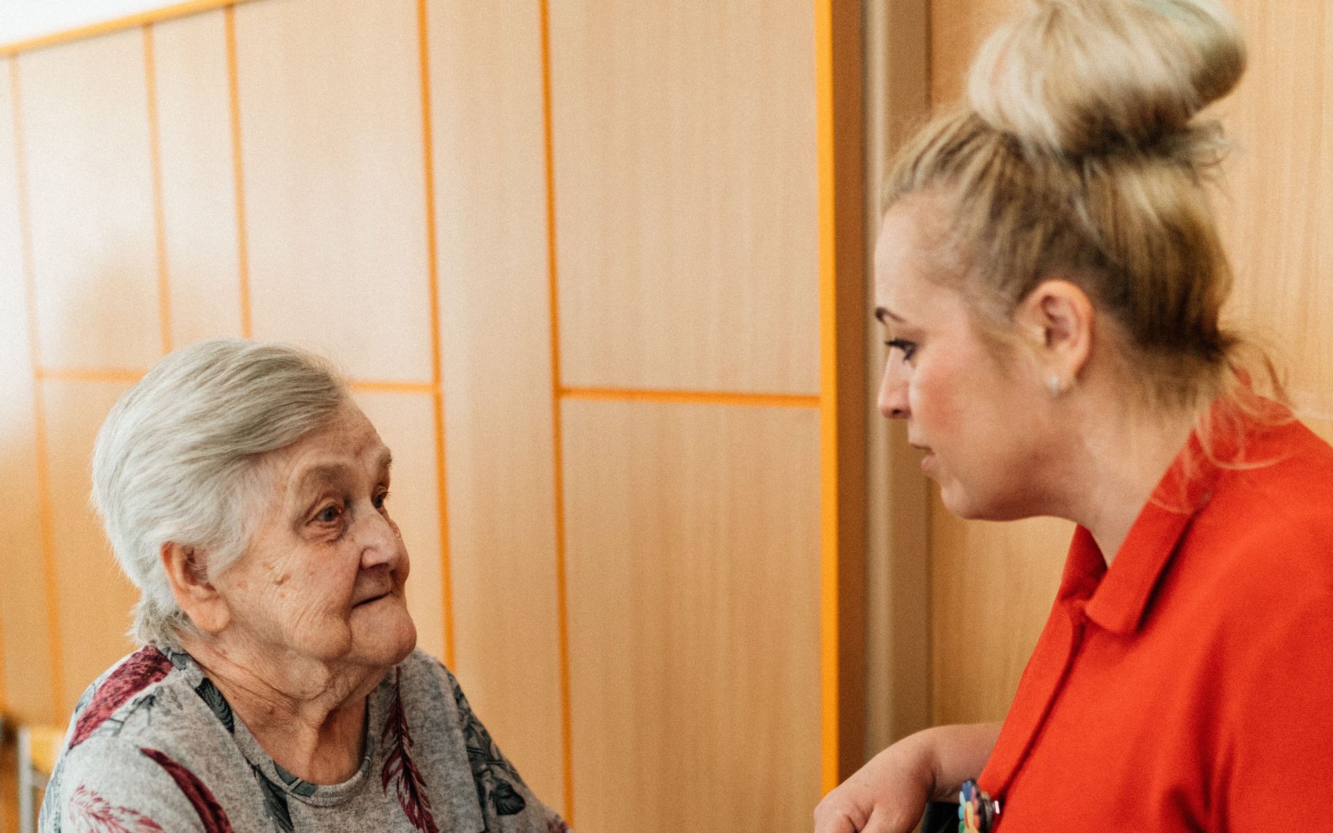 A caregiver supporting a resident's mobility with a walker in a community care setting, reflecting the daily support at Northern Edge Transitional Care.